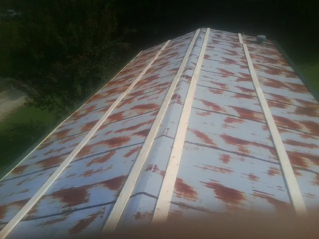 Rusted metal roof panels with new wood purlins before replacement — Storm Damage Roof Repair in Porterdale by Roofing Brothers