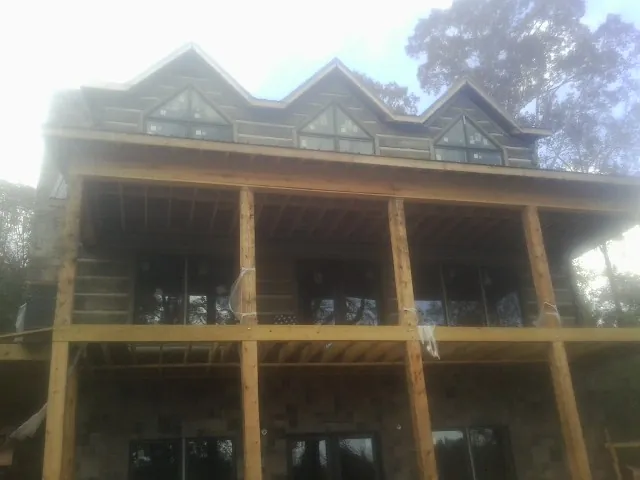 Dormers and porch framing on a large log home under construction — Roof Coating work by our crew in Porterdale