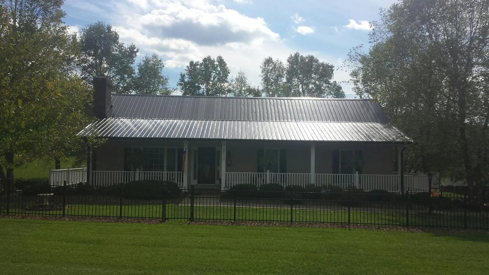 Gray metal roof on a brick ranch with a full width front porch — Gutter Guard Installation work by our crew in Porterdale