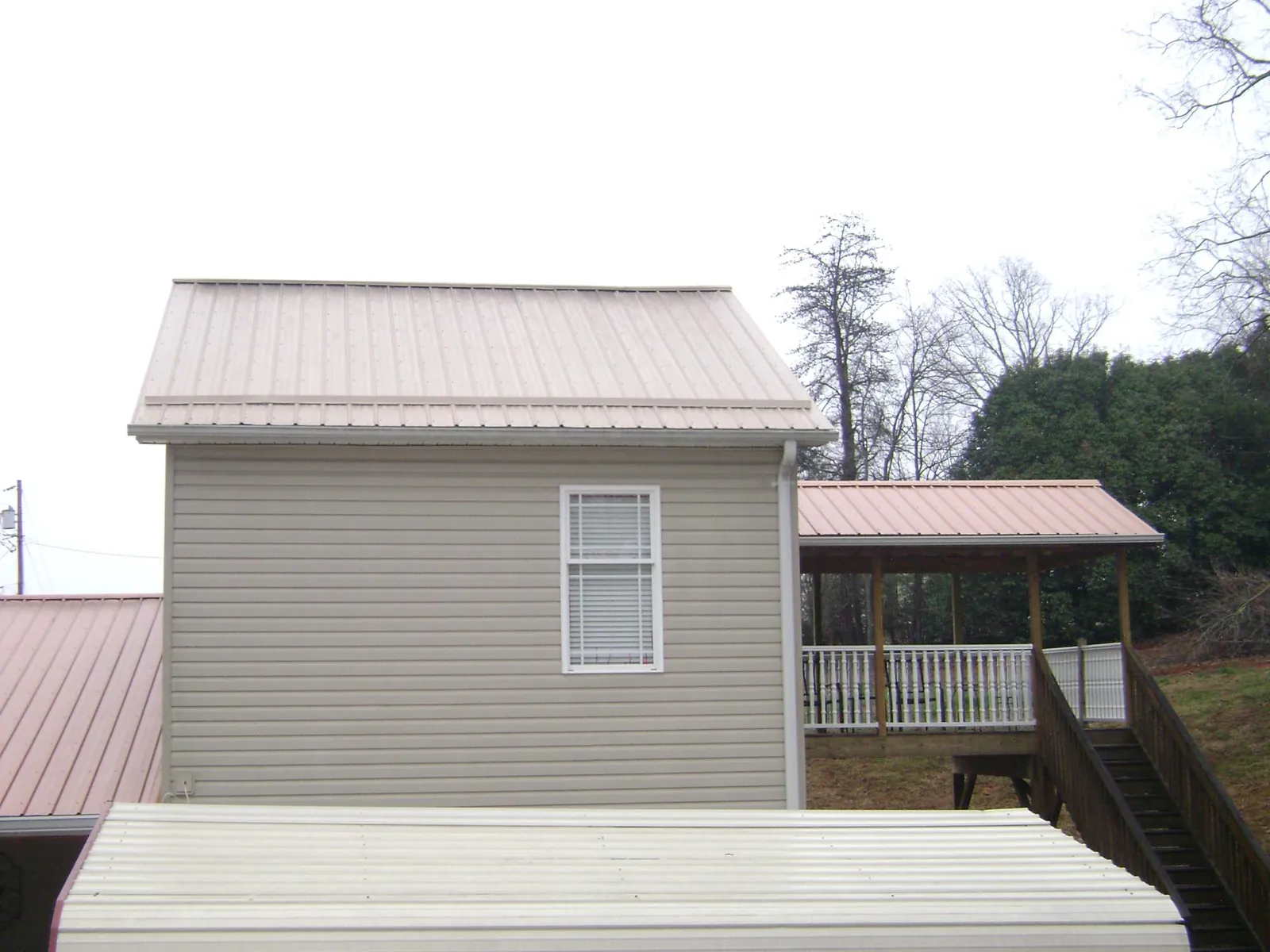 Tan metal roofs on a two story addition and attached porch, from a Roof Replacement job in Porterdale